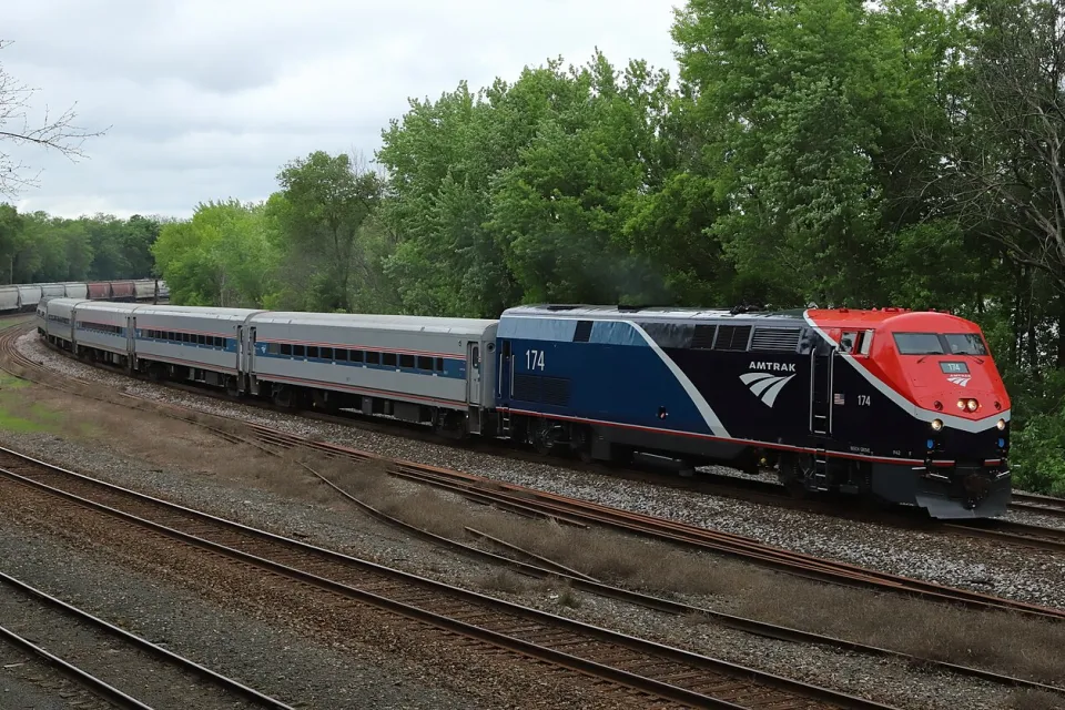 Amtrak Borealis train passing by green forest in Hastings, Minnesota.